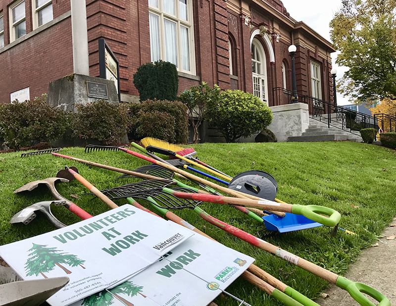 Volunteer signs, shovels and rakes lay in grass of brick Clark County Historical Museum